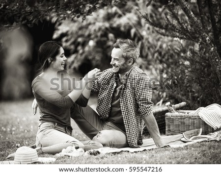 Young couple sitting on grass during a picnic. Black and white picture