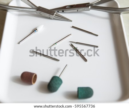 Medical instrument. Burs for podoiogy, red and green caps, cutters on the white medical tray