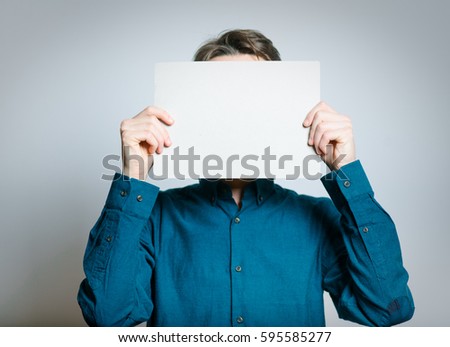 Business man hiding behind a white banner, isolated on a gray background