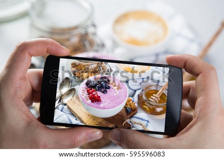 Taking photos of breakfast to phone. Social media concept. Sharing healthy food photos