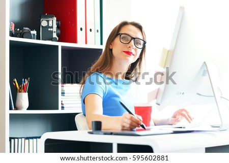 Female artist drawing something on graphic tablet at the home office