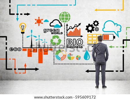 Rear view of a businessman looking at colorful business sketch drawn on a concrete wall. Concept of infographics and information presentation.