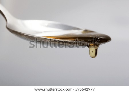 Honey pouring from a spoon against a light background