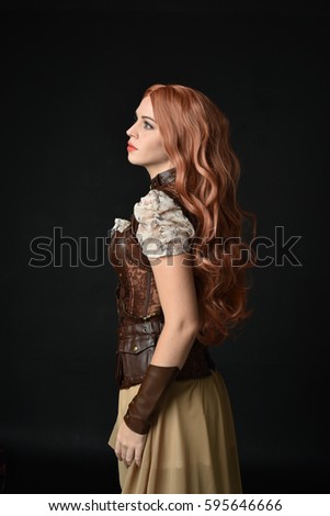 portrait of a young lady wearing a brown steampunk inspired outfit. black studio background.