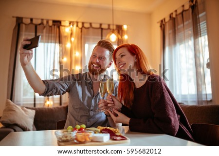 Portrait of a happy young couple enjoying at dinner together and taking photos at home.
