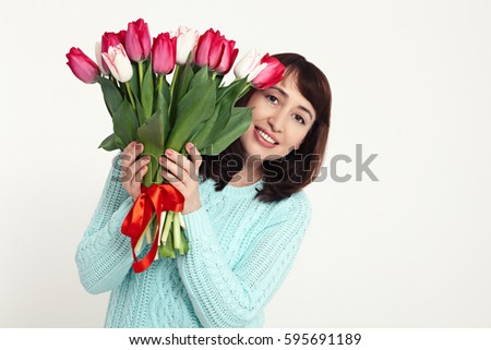 Beautiful woman in the blue dress with flowers tulips in hands on white background