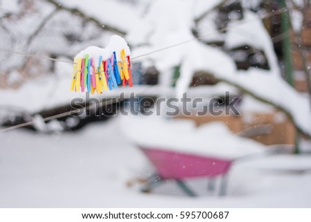 plastic varicoloured clothes pins on the rope in winter snowy day with snowflakes
