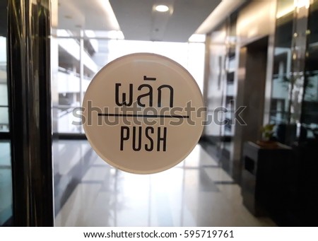 PUSH sign on glass opened door with metallic door handle.