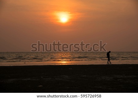 Silhouette man walking on the beach with sunset background 