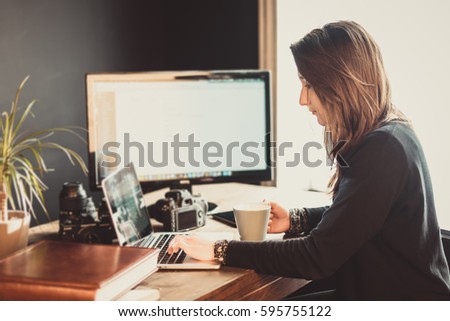 Young passionate woman photographer editing pictures in a photographic studio
