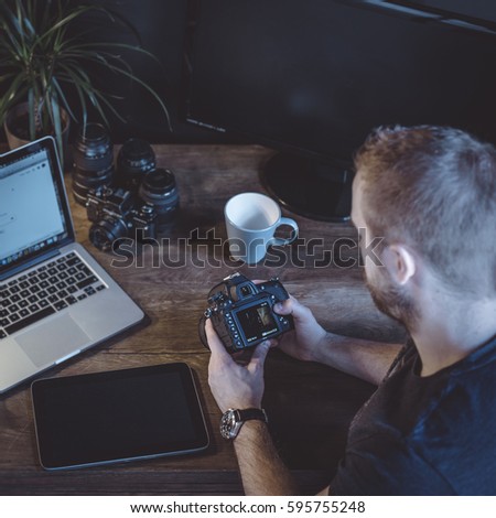 young man photographer editing pictures in his home office