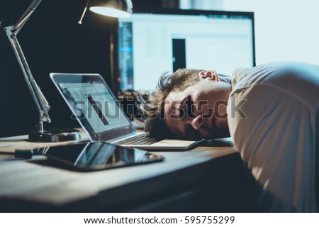 stressed young business man sleeping on his laptop in his office Royalty-Free Stock Photo #595755299