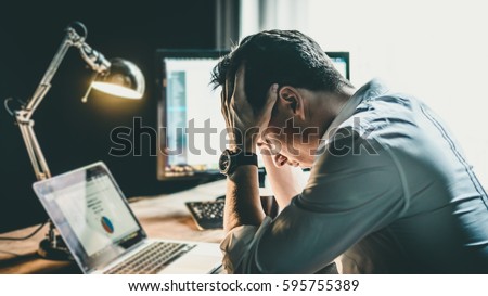 Tired and worried business man at workplace in office holding his head on hands after late night work, concept Royalty-Free Stock Photo #595755389