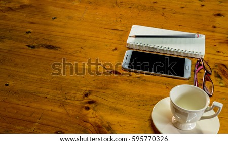 work place with note book,pencil;smart phone and cup of coffee on wooden table