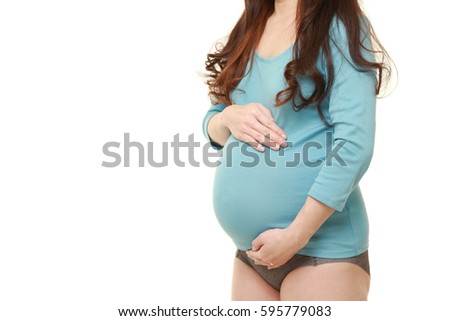 pregnant woman wearing blue shirt touching her belly on white background