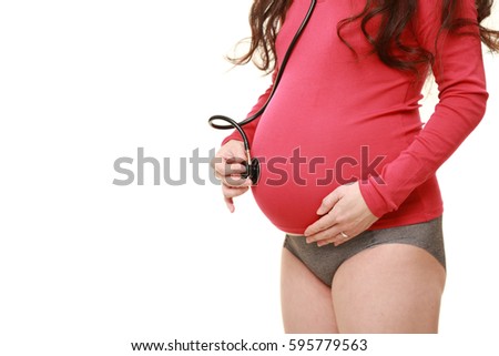 pregnant woman in a red shirt listen for belly by stethoscope