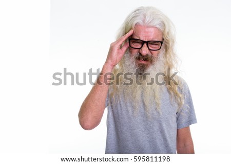 Studio shot of senior bearded man wearing eyeglasses while having headache
