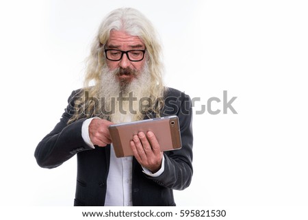 Studio shot of senior bearded businessman using digital tablet
