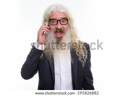 Studio shot of happy senior bearded businessman smiling while talking on mobile phone