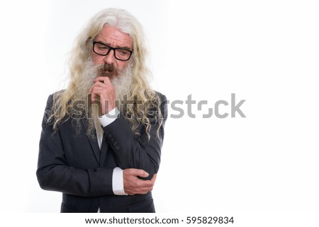 Studio shot of senior bearded businessman thinking while looking sad