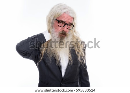 Studio shot of stressed senior bearded businessman having neck pain