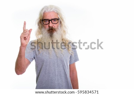 Studio shot of senior bearded man wearing eyeglasses while pointing finger up