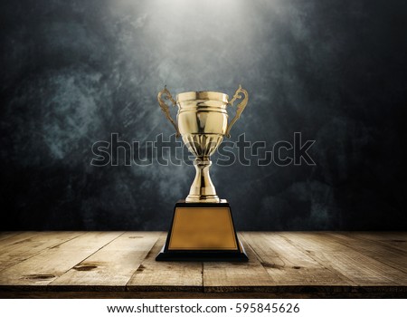 champion golden trophy placed on wooden table with dark background copy space ready for your design win concept. Royalty-Free Stock Photo #595845626