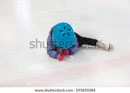 Toddler girl learning how to ice skate on in door ice arena.