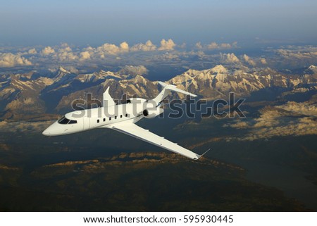 Business jet airplane flying over mountains. Royalty-Free Stock Photo #595930445