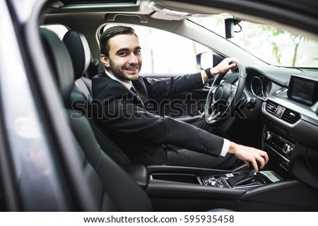 transport, business trip, destination and people concept - close up of young man in suit driving car look at camera Royalty-Free Stock Photo #595935458