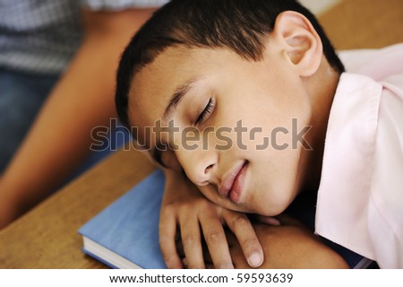 Kid in classroom on desk falling asleep on his notebook