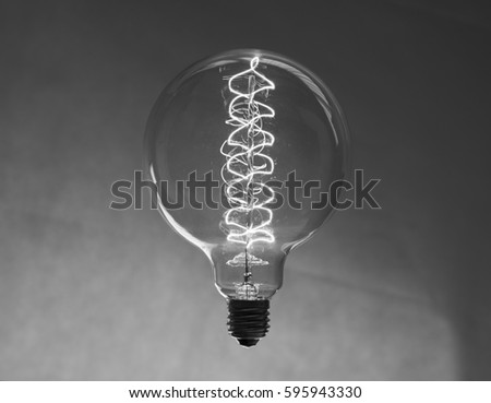 Light bulb hanging by thin wire then inverted and then converted to black and white.