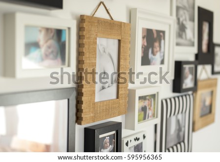 white wall with photos of the family in various photo frames Royalty-Free Stock Photo #595956365