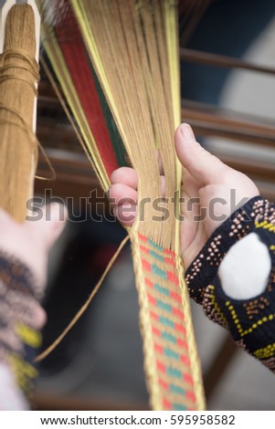 Hands of woman in action weaving traditional Lithuanian ethnic band from linen
