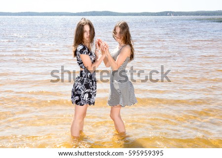 Attractive twins sisters with the foot on the sea in summer day