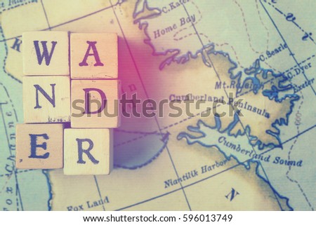 Wander word made from wooden letter blocks on a vintage map. Travel, holiday concept