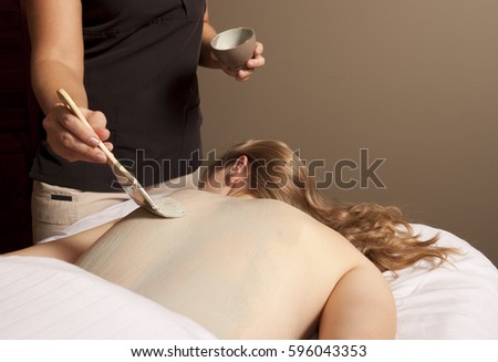 Massage therapy theme photo. Massage therapist applies a mud treatment.