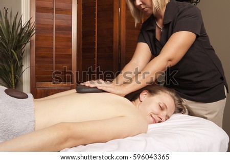 Massage therapy theme photo. Massage therapist using hot rocks on back.