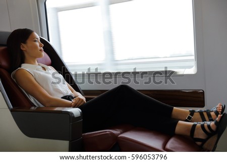 Elegant lady relaxing in comfortable first class seat with more legroom in train during travel. Asian woman lying down enjoying transport to urban city destination. Royalty-Free Stock Photo #596053796