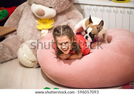 Portrait of teenage girl, with braids on head, smiling and laughing. Near to her pet dog. Image with selective focus