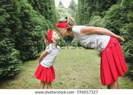 Mother leans to her daughter dressed in white and red clothes