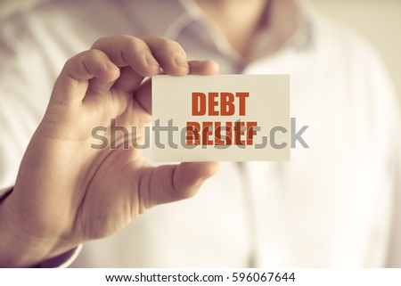 Closeup on businessman holding a card with text DEBT RELIEF, business concept image with soft focus background and vintage tone