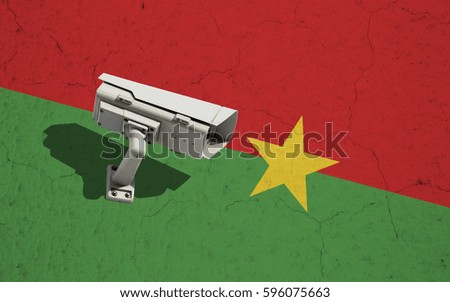CCTV security camera on wall with cracks painted in colors of Burkina Faso flag