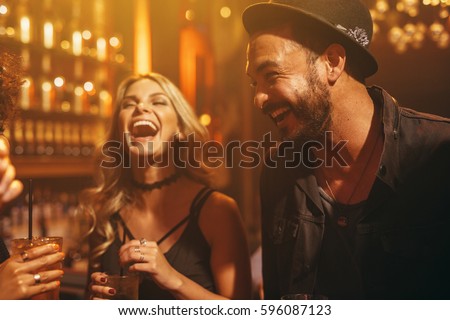 Group of people in the pub having fun. Young friends enjoying a night in club. Royalty-Free Stock Photo #596087123