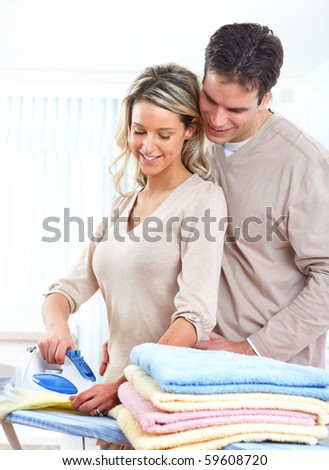 Happy young beautiful woman ironing clothes. Housework