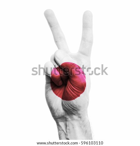 Japan national flag painted onto a male hand showing a V peace sign