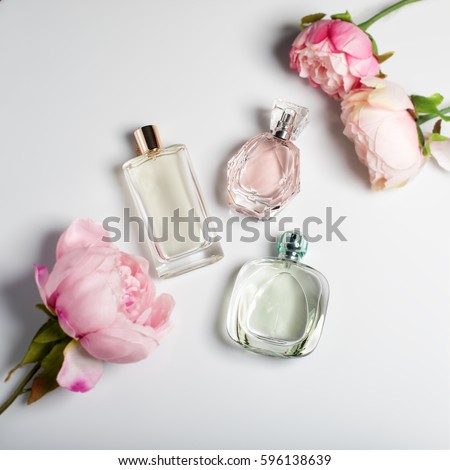 Perfume bottles with flowers on light background. Perfumery, cosmetics, fragrance collection. Flat lay Royalty-Free Stock Photo #596138639