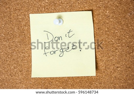 Paper note written with Don't Forget inscription on cork board.