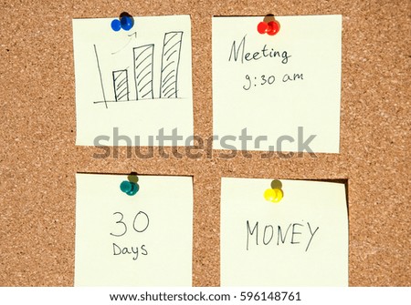 Several paper note with text on the cork board close-up.