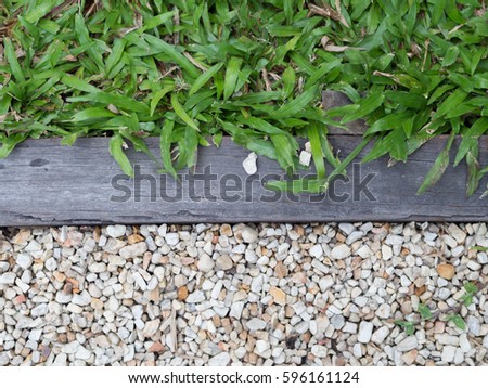 natural paving background texture with green grass and stone pebble separates with wood Royalty-Free Stock Photo #596161124